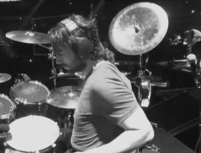 A Man Wearing Headphones Is Playing Drums On A Stage GIF