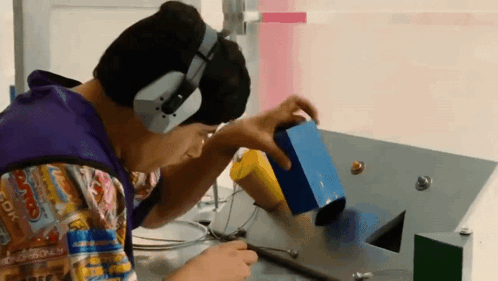 A Man Wearing Headphones Is Playing With A Toy On A Table GIF