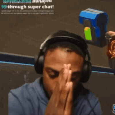 A Man Wearing Headphones Is Praying In Front Of A Sign That Says " See A Donation Donated Through Super Chat " GIF