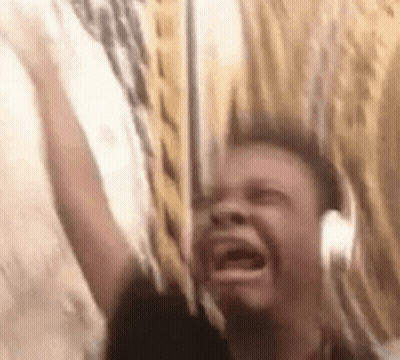 A Man Wearing Headphones Is Screaming While Holding A Sword . GIF