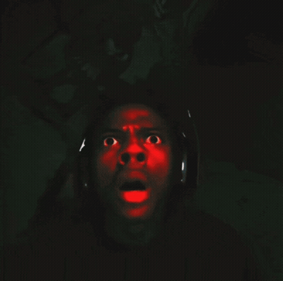 A Man Wearing Headphones Is Screaming With A Red Light Projected On His Face GIF