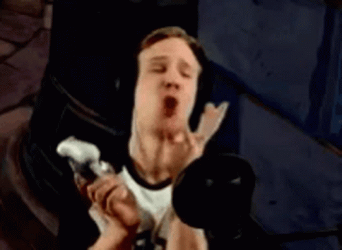 A Man Wearing Headphones Is Singing Into A Microphone In A Dark Room . GIF