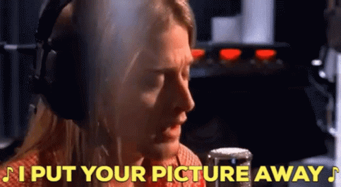 A Man Wearing Headphones Is Singing Into A Microphone With The Words " I Put Your Picture Away " Behind Him GIF