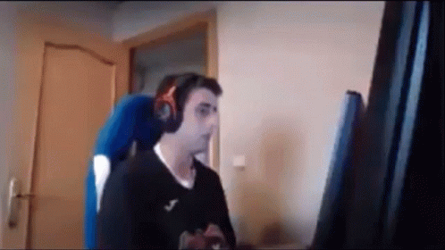 A Man Wearing Headphones Is Sitting In A Chair In Front Of A Computer Monitor . GIF
