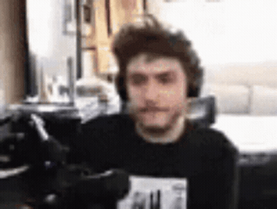 A Man Wearing Headphones Is Sitting In Front Of A Computer Screen . GIF