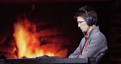 A Man Wearing Headphones Is Sitting In Front Of A Fireplace GIF
