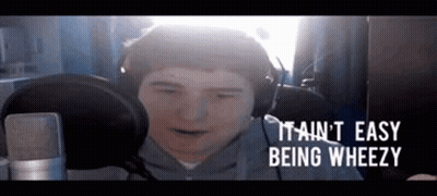 A Man Wearing Headphones Is Sitting In Front Of A Microphone And Making A Funny Face . GIF