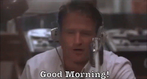 A Man Wearing Headphones Is Sitting In Front Of A Microphone And Says `` Good Morning '' . GIF