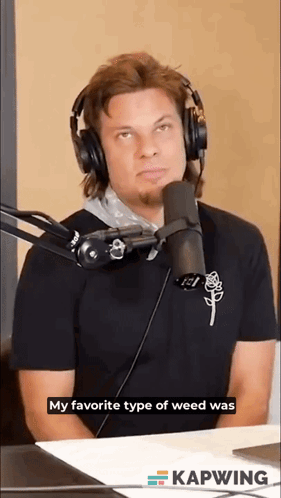 A Man Wearing Headphones Is Sitting In Front Of A Microphone And Talking Into It . GIF