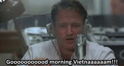 A Man Wearing Headphones Is Sitting In Front Of A Microphone And Talking Into It . GIF