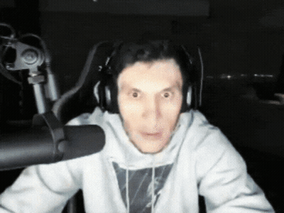 A Man Wearing Headphones Is Sitting In Front Of A Microphone Making A Funny Face GIF