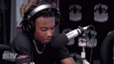 A Man Wearing Headphones Is Sitting In Front Of A Microphone That Says Big Tv On It GIF