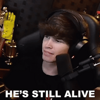 A Man Wearing Headphones Is Sitting In Front Of A Microphone With The Words He 'S Still Alive Written Below Him GIF