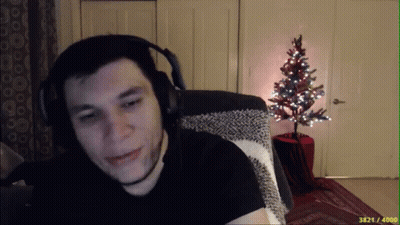 A Man Wearing Headphones Is Sitting In Front Of A Small Christmas Tree GIF