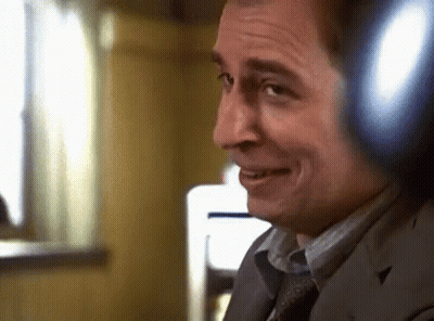 A Man Wearing Headphones Is Smiling And Looking At The Camera GIF