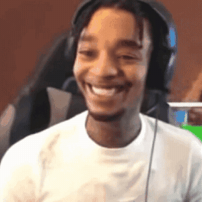 A Man Wearing Headphones Is Smiling And Looking At The Camera . GIF