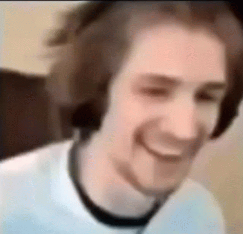 A Man Wearing Headphones Is Smiling And Looking At The Camera . GIF