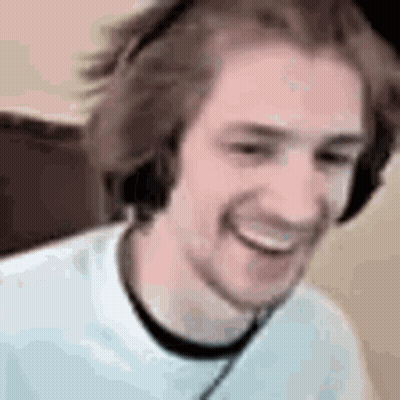 A Man Wearing Headphones Is Smiling While Sitting In Front Of A Computer . GIF