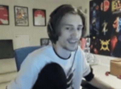A Man Wearing Headphones Is Smiling While Sitting In Front Of A Computer In A Room . GIF