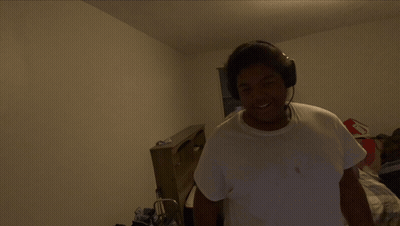 A Man Wearing Headphones Is Standing In A Room GIF