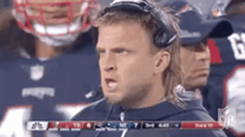 A Man Wearing Headphones Is Standing In Front Of A Football Team . GIF
