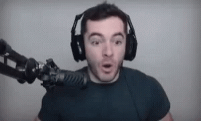 A Man Wearing Headphones Is Standing In Front Of A Microphone And Making A Funny Face . GIF