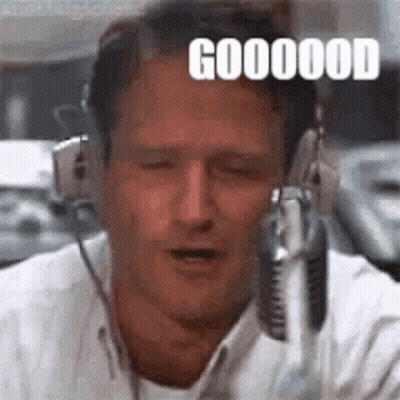 A Man Wearing Headphones Is Talking Into A Microphone And Making A Funny Face . GIF