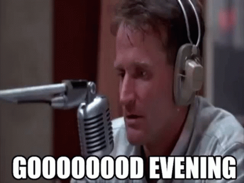 A Man Wearing Headphones Is Talking Into A Microphone And Saying `` Good Evening '' . GIF