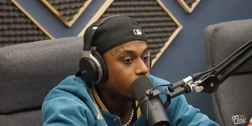A Man Wearing Headphones Is Talking Into A Microphone With The Word Flow On The Bottom GIF