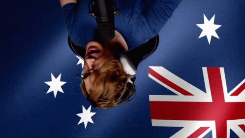 A Man Wearing Headphones Is Upside Down In Front Of A Flag GIF