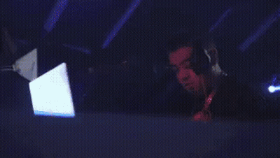 A Man Wearing Headphones Is Using A Laptop In A Dark Room GIF