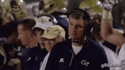 A Man Wearing Headphones Is Watching A Football Game With A Group Of People . GIF