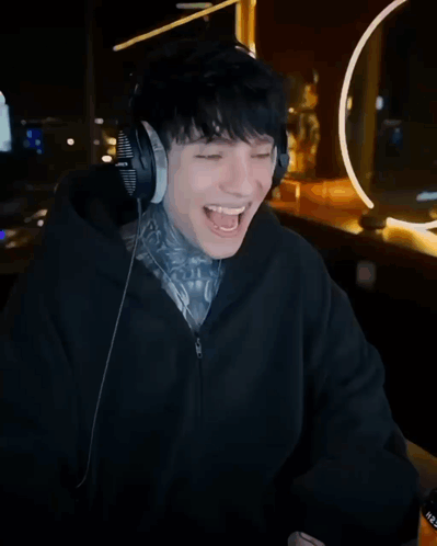 A Man Wearing Headphones Laughs In Front Of A Poster That Says Kick And Cry GIF