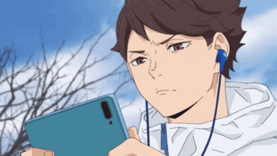 A Man Wearing Headphones Looks At His Phone GIF