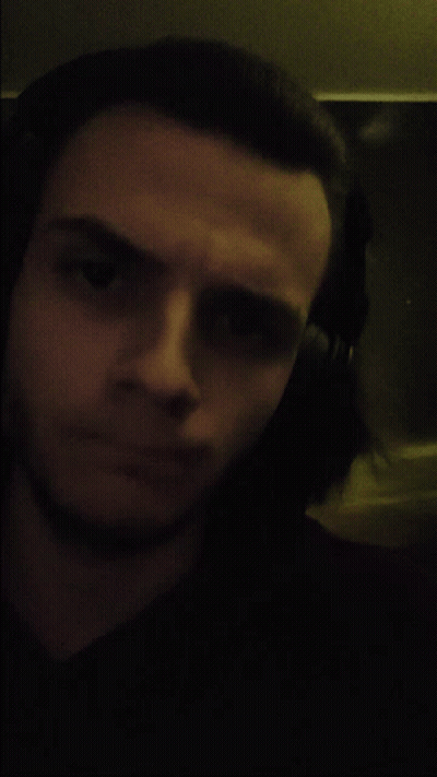 A Man Wearing Headphones Looks At The Camera In A Dark Room GIF