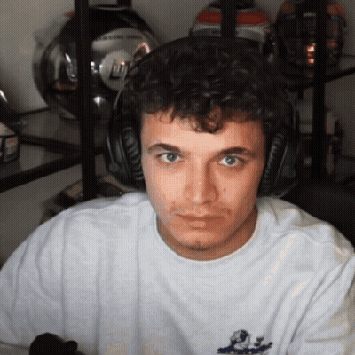 A Man Wearing Headphones Looks At The Camera In Front Of A Shelf Of Helmets GIF