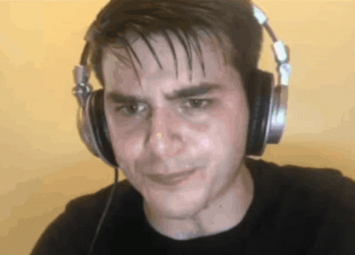 A Man Wearing Headphones Looks At The Camera With A Sad Look On His Face GIF