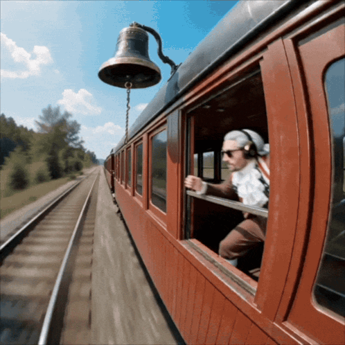 A Man Wearing Headphones Looks Out A Train Window GIF