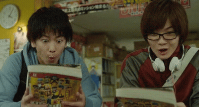 A Man Wearing Headphones Looks Surprised While Another Man Looks At A Book GIF