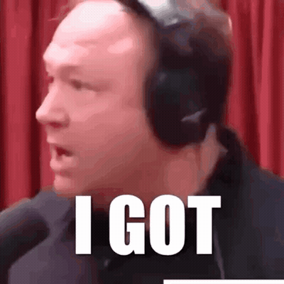 A Man Wearing Headphones Says I Got In Front Of A Red Curtain . GIF