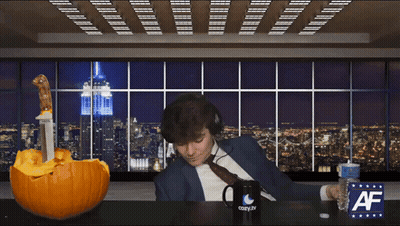 A Man Wearing Headphones Sits At A Table With A Cozy.tv Mug And A Pumpkin GIF