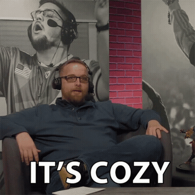 A Man Wearing Headphones Sits In A Chair With The Words " It 'S Cozy " On The Bottom GIF