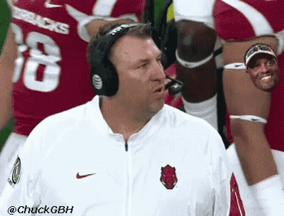 A Man Wearing Headphones Stands In Front Of A Football Player Wearing A Jersey With The Number 18 GIF