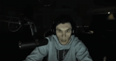 A Man Wearing Headphones Stands In Front Of A Microphone And Looks Surprised GIF
