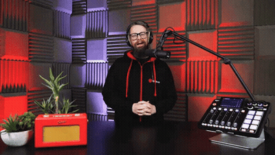 A Man Wearing Headphones Stands In Front Of A Microphone And Mixer GIF