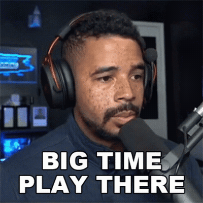 A Man Wearing Headphones Stands In Front Of A Microphone And Says Big Time Play There GIF