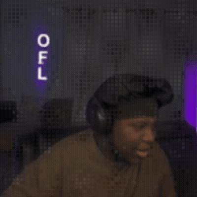A Man Wearing Headphones Stands In Front Of A Neon Sign That Says Off GIF