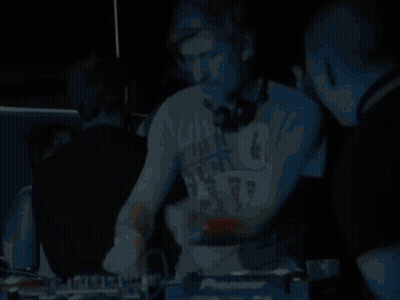 A Man Wearing Headphones Stands In Front Of A Pioneer Dj Controller GIF