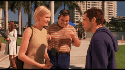A Man Wearing Headphones Talks To Two Women GIF