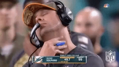 A Man Wearing Headphones Watches A Football Game Between The Miami Dolphins And The San Francisco 49Ers . GIF